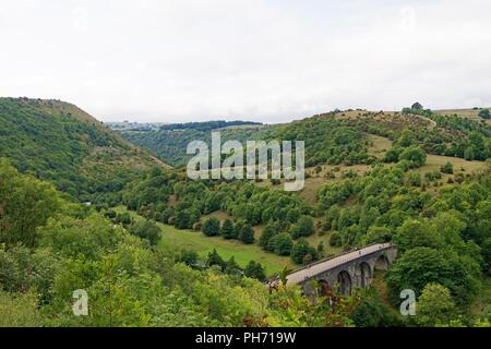Die Erfassung der ehrfürchtige Maßstab der grünen und fruchtbaren Monsal Tal, dass Zwerge eine umfangreiche Eisenbahnviadukt, im Peak District. Stockfoto