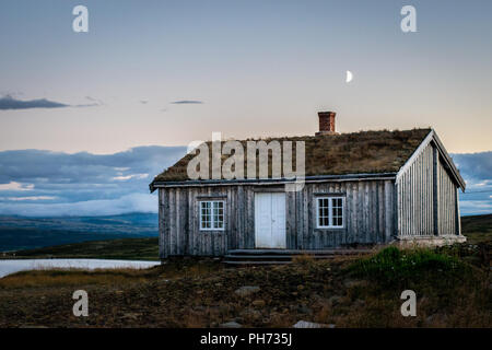 Ein altes Haus mit der Mond gerade über den Schornstein bei Sonnenuntergang in Storwartz, außerhalb von Røros (ROROS), Norwegen. Stockfoto