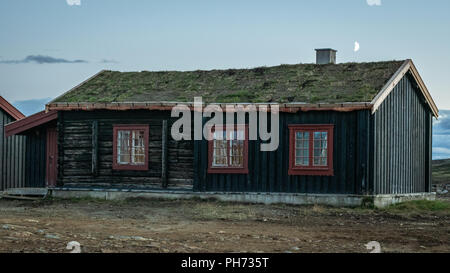 Ein altes Haus mit der Mond gerade über den Schornstein bei Sonnenuntergang in Storwartz, außerhalb von Røros (ROROS), Norwegen. Stockfoto