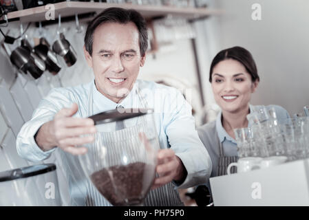 Lächelnd baristas Gefühl interessiert, die während der Arbeit mit einer neuen Kaffeemaschine Stockfoto