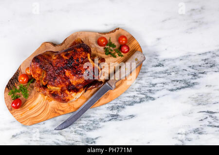 Großes ganzes Huhn bereit, auf Holzbrett serviert zu werden. Stockfoto