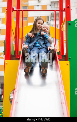 Mädchen Rutschen hinunter den Hügel auf dem Spielplatz Stockfoto