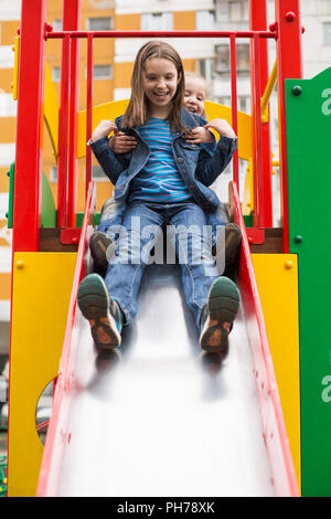 Mädchen Rutschen hinunter den Hügel auf dem Spielplatz Stockfoto