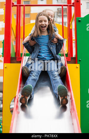 Mädchen Rutschen hinunter den Hügel auf dem Spielplatz Stockfoto