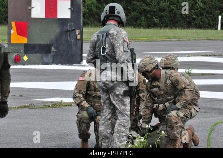 Sgt. 1. Klasse John Scholes, ein Flug medic zu Delta Unternehmen, 1.Staffel, 376 Aviation Battalion, Nebraska Nationalgarde zugewiesen links oben mit der grafenwoehr Armee Gesundheit Klinik medizinisches Team zu den Eseln und einer simulierten Prep/Unfall ein hebezeug Betrieb, nachdem er 100 Fuß auf den Boden von einem UH-72A Lakota bei Grafenwöhr Training Area gesenkt wurde, Deutschland, 21. Juni, 2018. Die Nebraska und Iowa National Guard Soldaten sind Teil eines vier Monate rotational Bereitstellung nach Deutschland, wo sie die reale Welt MEDEVAC Mission für Hohenfels und Grafenwöhr aus Ihrer aktiven Kollegen übernehmen. Stockfoto