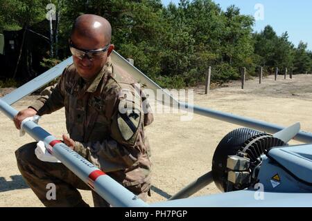 Spc. Osvaldo Gierbolini, ein unbemanntes Flugzeug system Betreuer auf den Reiter platoon Delta Firma zugewiesen, 91st Brigade Ingenieur Bataillon, 1st Armored Brigade Combat Team, 1.Kavallerie Division, reinigt die hinteren Kotflügel eines RQ-7B Shadow UAS im Reiter Flug Landeplatz in Zagan, Polen, 29. Juni 2018. Der platoon Die erste taktische UAS Flug in Polen. Sie sind derzeit zur Unterstützung der Atlantischen lösen in Europa eingesetzt. Stockfoto