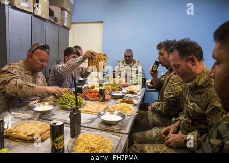 Der Provinz Helmand, in Afghanistan (25. Juni 2018) - britische Soldaten mit der entschlossenen Unterstützung der Zentrale, zugeordnet zu der Armee institutionellen Advisor Team (AIAT) und des US Marine Corps Berater mit Task Force Südwesten teilen sich eine Mahlzeit mit Oberst Shah Wali, Kommandant der afghanischen nationalen Armee Korps 215 regionalen militärischen Ausbildungszentrums (RMTC) am Lager Shorabak. Die AIAT sprach mit ANA Soldaten über ihre Zuweisungen auf der Front ein Verständnis darüber, welche Arten von Ausbildung vorteilhaft für die Zukunft kandaks durch RMTC wäre zu entwickeln. Stockfoto