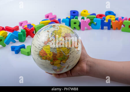 Kleines Modell gobe in Hand mit bunten Buchstaben hinter Stockfoto