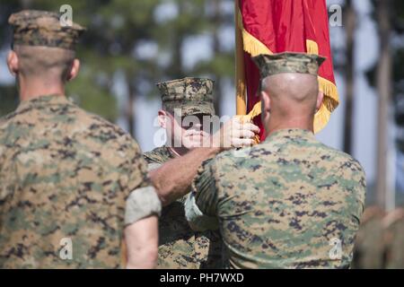 Us Marine Sgt. Maj. Sean E. Spatar, Sergeant Major des Marine Corps Combat Service Support Schulen (MCCSSS), Mitte, stellt der Befehl Farben zu Oberst David S. Grant, ausgehende kommandierender Offizier der MCCSSS, rechts, während der MCCSSS Ändern des Befehls Zeremonie am Lager Johnson, N.C., 21. Juni 2018. Die Änderung der comand-Zeremonie ist eine altehrwürdige Tradition, in der man Commander Behörde zu einer anderen verzichtet. Stockfoto