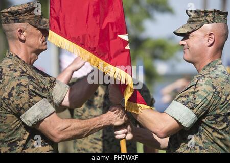 Us Marine Oberst James L. Shelton jr., eingehende kommandierender Offizier der Marine Corps Combat Service Support Schulen, Links, führt der Befehl Farben zu Oberst David S. Grant, ausgehende kommandierender Offizier der MCCSSS, rechts, während der MCCSSS Ändern des Befehls Zeremonie am Lager Johnson, N.C., 21. Juni 2018. Die Änderung des Befehls Zeremonie ist eine altehrwürdige Tradition, in der man Commander Behörde zu einer anderen verzichtet. Stockfoto