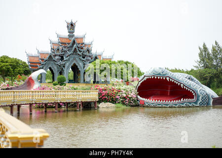 Graue Wand und orange Dach der Pavillon in der Mitte der Pool, mit Big fish Statue in um ihn herum, Thailand glaube Geschichte. Stockfoto