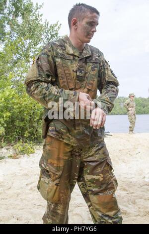 Us-Armee finden Sgt. Justin Richardson, eine chemische Vorgänge biologische Verbot team leader von Anchorage, Alaska, mit der 365 Chemical Company, 416th Theater Ingenieur Befehl versucht, das überschüssige Wasser aus seiner Uniform zu erhalten, nach dem Schwimmen über Mott See während Mystery event Tag 5 bei der US-Army Reserve 2018 besten Krieger Wettbewerb in Fort Bragg, North Carolina, 14. Juni 2018. Heute, U.S. Army Reserve Soldaten geben alles, was sie haben, ihre Grenzen bringen und am letzten Tag des Events in den Wettbewerb beenden. Stockfoto