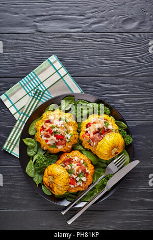 Gebackene Pattypan squash gefüllt mit Reis, gebratenes Hühnerfleisch, knusprig gebratener Speck, Paprika und frischen Spinat serviert mit grünen Blättern und Petersilie auf Stockfoto