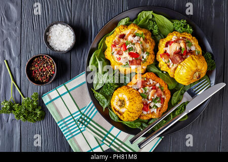 Close-up von gebackenen Pattypan squash gefüllt mit Reis, gebratenes Hühnerfleisch, knusprig gebratener Speck, rote Paprika und Serviert mit Spinat Blätter und parsl Stockfoto
