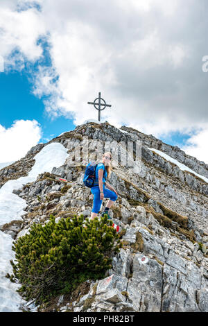 Weibliche Wanderer auf den Spuren der Seekarspitz, hinter dem Gipfel mit Gipfelkreuz des Seekarspitz, Tirol, Österreich Stockfoto