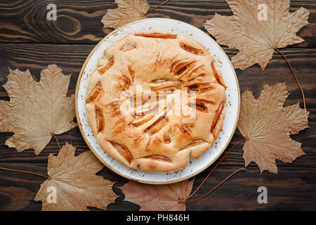 Leckere hausgemachte Saison Apple Pie von Ahorn Laub umgeben. Herbst Bäckerei, gemütliche Feiertage. Stockfoto