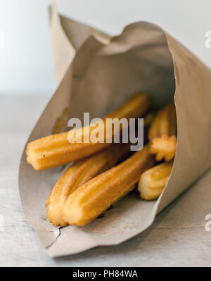 Traditionelle spanische Dessert Churros in braunem Papier Kegel. Ein churro ist ein gebraten - Teig Gebäck basierte Snack. Seine Oberfläche ist Ridged Wegen geleitet. Stockfoto