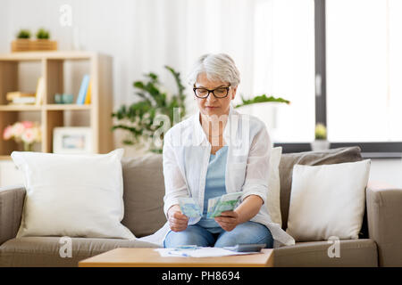 Ältere Frau zählen Geld zu Hause Stockfoto