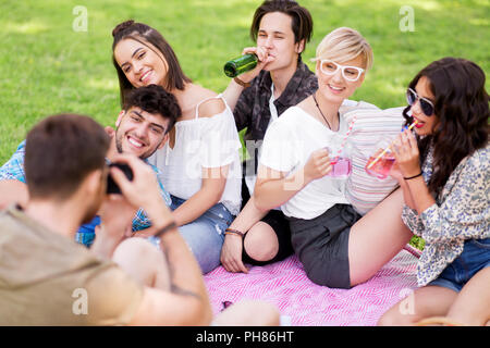 Freunde fotografieren im Sommer Picknick im Park Stockfoto