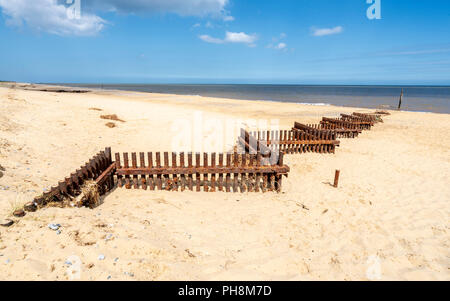 Rostigem Eisen Sturm Verteidigung Barrieren auf einem sandigen Strand von Norfolk in Großbritannien Stockfoto