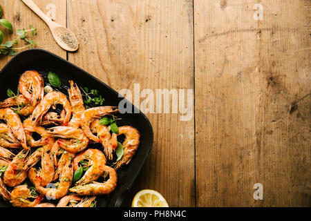 Lecker lecker gebratene Garnelen mit Gewürzen auf Pan mit Zutaten aus hölzernen Tisch. Ansicht von oben mit Platz kopieren. Essen Hintergrund italienische Küche Stockfoto