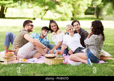 Freunde fotografieren im Sommer Picknick im Park Stockfoto