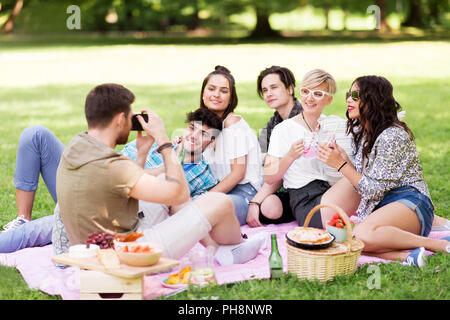 Freunde fotografieren im Sommer Picknick im Park Stockfoto