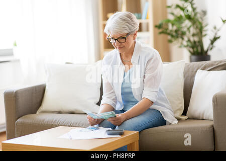 Ältere Frau zählen Geld zu Hause Stockfoto