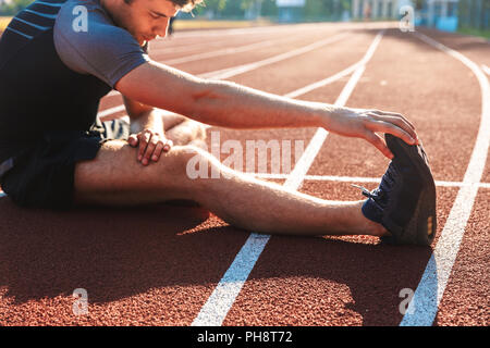 Zugeschnittenes Bild der starken Sportler tun Dehnübungen im Stadion Stockfoto