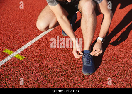 Nahaufnahme von einem jungen Sportler Schnürsenkel binden im Stadion Stockfoto