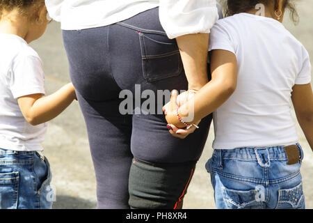 Mutter Überqueren der Straße hält die Hand ihrer Kinder Stockfoto