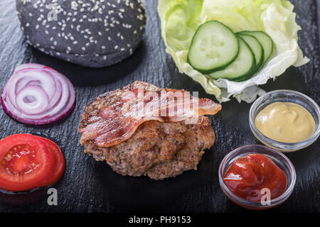 Zutaten für einen Hamburger auf schwarzem Schiefer Stockfoto
