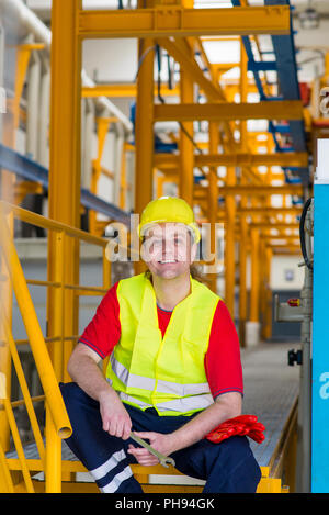 Ein Arbeiter in einer Fabrik ruhen und schauen sich eine Kamera Stockfoto