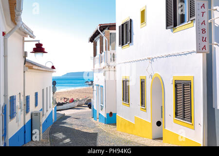 Romantische kleine Gasse mit bunten Häusern, die zu einem Sandstrand mit Fischerboot und Meerblick Stockfoto