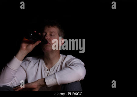 Reifer Mann trinkt ein Bier in dunklen Hintergrund gedrückt Stockfoto