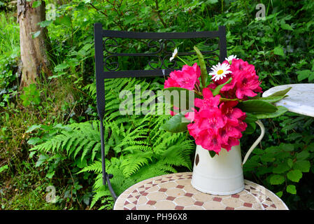 Alten Stuhl im Garten mit Blumen Stockfoto