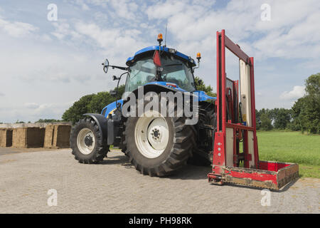 Blaue Traktor mit einem roten bale Slicer Stockfoto