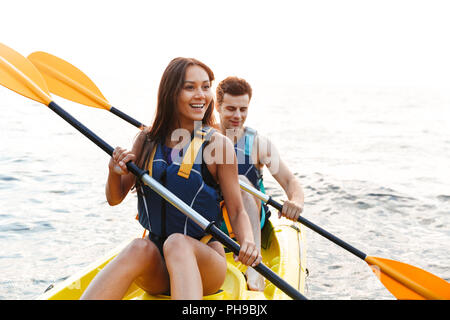 Schöne junge Paar Kajakfahren auf dem See zusammen und lächelnd Stockfoto