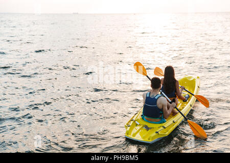 Zurück Blick auf eine attraktive junge Paar Kajakfahren auf dem See zusammen Stockfoto