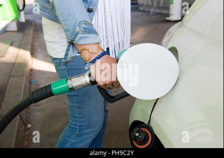 Eine Frau ist ihr Auto mit Kraftstoff an der Tankstelle befüllen. Stockfoto