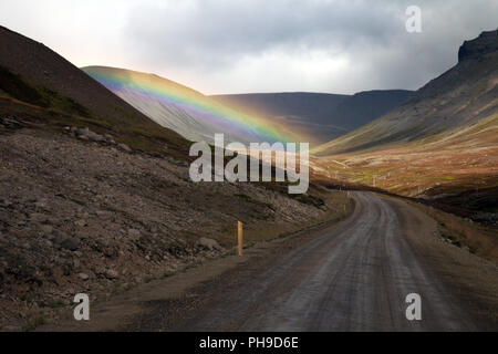 Regenbogen über einer Straße in den Bergen, Westfjorde, Island Stockfoto