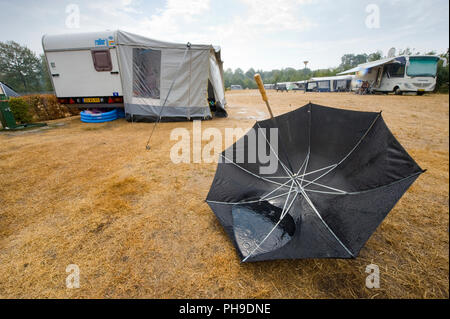 HAAKSBERGEN, Niederlande - 09.August 2018: Ein Regenschirm ist auf dem Kopf liegend auf dem Boden nach einem Regenguss auf einem niederländischen Camping im Sommer. Stockfoto