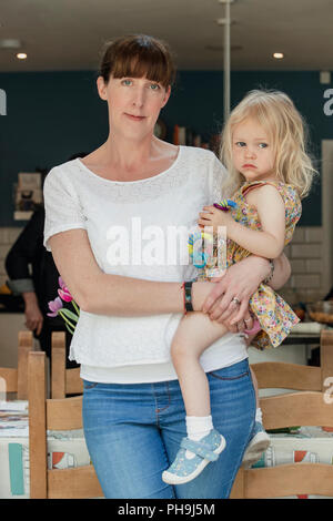 Porträt einer Mitte nach Mutter und ihrer Tochter in die Kamera schaut. Die Mutter, die ihre Tochter an der Seite von ihr. Sie stehen Innen Stockfoto