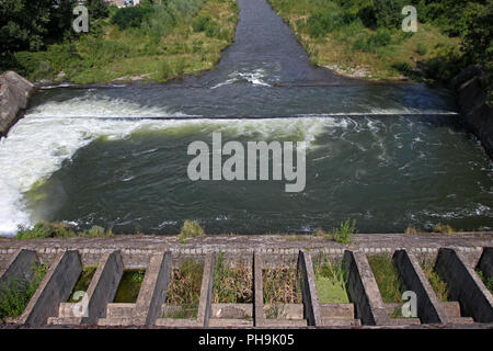 Staumauer und Überlauf von Iskar Dam. Wasser fließt über eine Staumauer. Nebel über der Iskar Staumauer. Kaskade von einem Wasserkraftwerk. See ... Stockfoto