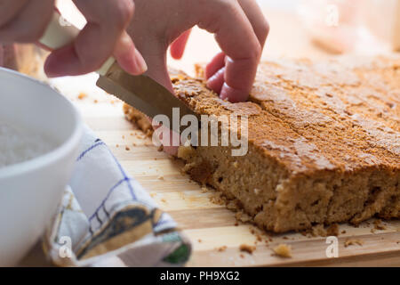 Weibliche Hände schneiden und vorbereiten Kuchen Kruste Stockfoto