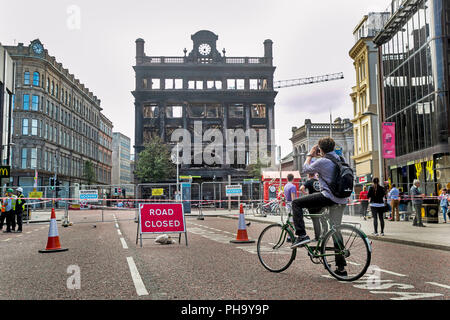 Ein Radfahrer nimmt ein Foto der historischen 5-stöckigen Bank Gebäude im Stadtzentrum von Belfast, wo ein Großbrand im Primark Store auf Dienstag brach. Stockfoto