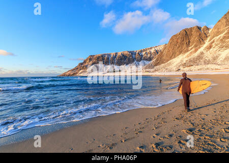 Surfer mit Surfbrett am Strand, Unstad, Vestvagoy, Lofoten, Nordland, Norwegen, Europa Stockfoto