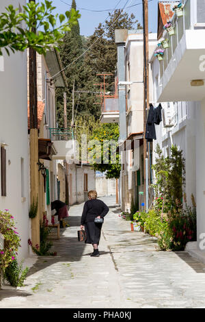 Dame in traditioneller Kleidung Wandern in einer ruhigen Straße im historischen Dorf Omodos im Troodos-gebirge, Zypern, Europa Stockfoto