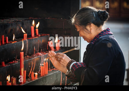 Frau Beleuchtung Kerzen an Yuantong buddhistischen Tempel, Kunming, Provinz Yunnan, China, Asien Stockfoto