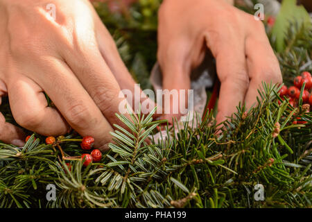 Floristen binden echten Adventskranz - Nahaufnahme Weihnachten Dekoration Stockfoto